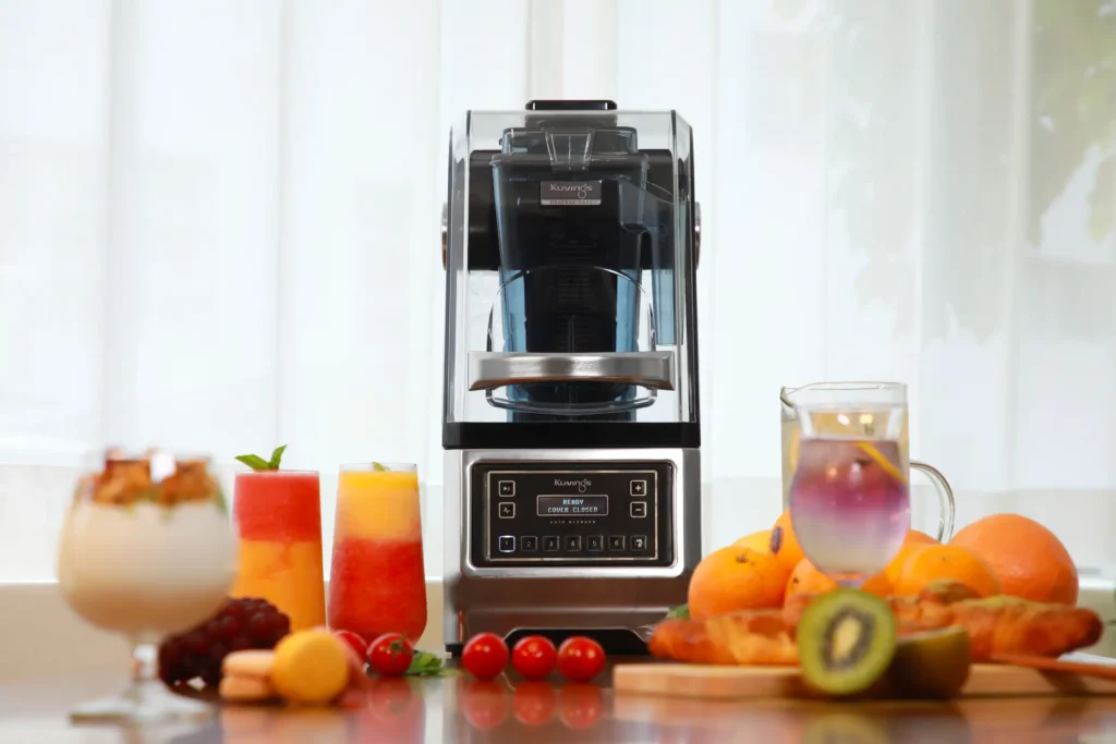 Kuvings CB980 vakuumski blender na kuhinjskoj radnoj ploči sa svježim voćem i čašama soka